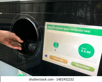 Sydney / Australia 08-16-2019. Return And Earn Public Return Point For Recycling. Reverse Vending Machine For Refund & Recycling Of Glass Bottles. Hand Holding A Bottle.  