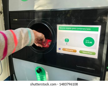 Sydney / Australia 08-16-2019. Return And Earn Public Return Point For Recycling. Reverse Vending Machine For Refund & Recycling Of Glass Bottles. Hand Holding A Bottle.  