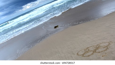 Sydney, Australia - Aug 7, 2016. Wave Approaches Olympic Rings Drawn In The Sand. Summer Olympic Games.