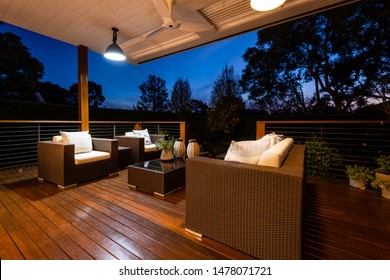 Sydney, Australia - August 1 2019: Luxury outdoor lounge area with chairs and cushions looking onto beautiful garden from a deck - shot at twilight