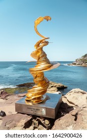 Sydney, Australia - Jan 2020: Art Sculpture Exhibition On Bondi Beach Coastal Walk. Melting Statue Of Liberty Concept. Gold Dramatic Artwork.