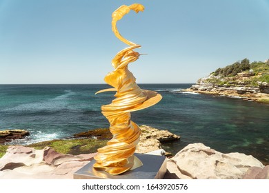 Sydney, Australia - Jan 2020: Art Sculpture Exhibition On Bondi Beach Coastal Walk. Melting Statue Of Liberty Concept. Gold Dramatic Artwork.