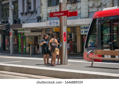 Sydney, Australia - January 26, 2020: People Using Tap On Tap Off Ticket Automation Machine At Chinatown Light Rail Station With Red Tramway Car On The Backgorund