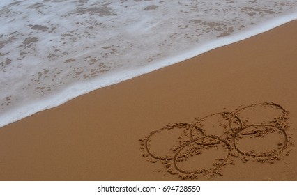 Sydney, Australia - Jul 31, 2016. Wave Approaches Olympic Rings Drawn In The Sand. Summer Olympic Games Rio 2016.