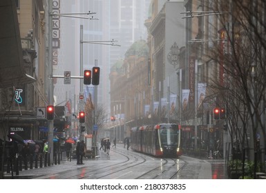 Sydney, Australia - July 19, 2022. A Light Rail Approaches Traffic Lights On George Street On A Rainy Winter's Day In Downtown Sydney.