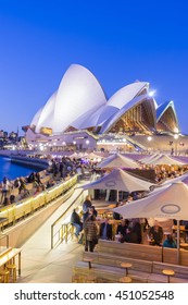 Sydney, Australia - June 25, 2016: View of cafe full of people and the Sydney Opera House at twilight. The cafe offers a stunning view of the Sydney Opera House.