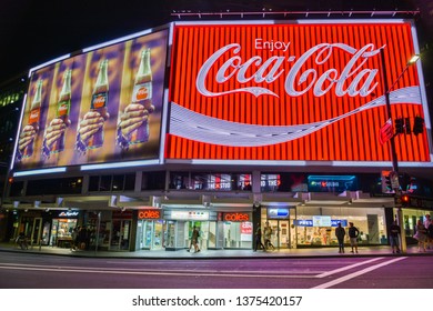 Sydney, Australia – March 9, 2017. The Coca-Cola Billboard In Kings Cross, Sydney, With Commercial Properties And People, At Night.