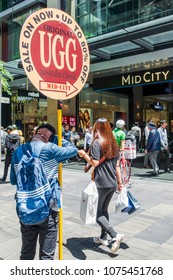 Sydney, Australia - Nov 14, 2017: A Man Holding Up A Sign On Martin Place, Drumming Up Sale Of Ugg Boots In Nearby Store. Ugg Boots Are Iconic Australian Footwear. People Walking Around In The Area.