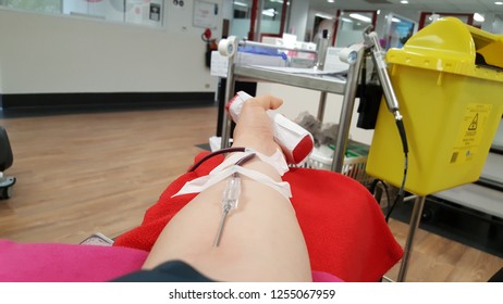 SYDNEY, AUSTRALIA - OCTOBER 22, 2018: Left Arm Of Asian Woman Volunteer Blood Donor Giving Blood With A Red Bouncy Holding In Left Hand During The Transfusion At Australian Red Cross Blood Service.