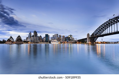 Sydney City CBD Landmarks Across Harbour From Houses To Bridge Arch At Blue Hour Of Sunrise When Lights Reflect In Still Waters