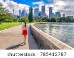 Sydney city girl tourist walking in urban park with skyscrapers skyline in the background. Australia travel vacation in the summer. Australian people lifestyle living.