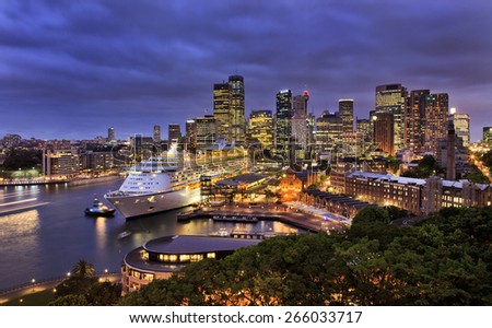 sydney harbour and city CBD at sunset with ocean liner at overseas terminal illuminated with lights