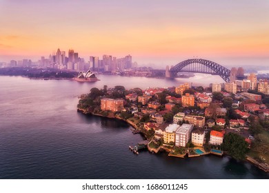 Sydney harbour and major city landmarks of waterfront around Sydney Harbour bridge in aerial view at pink sunrise.