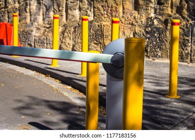 Sydney, New South Wales / Australia - August 07 2018: Car Park Boom Gate With Yellow Poles, Street And Rock In Background