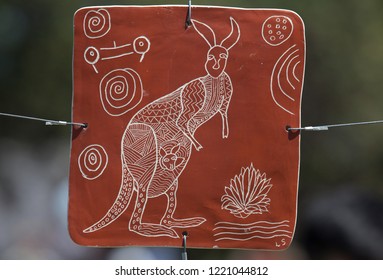 Sydney, New South Wales / Australia - October 27 2018: P\close Up Of Plate With Aboriginal Art Showing Kangaroo During Sculpture By The Sea Exhibition With Blurred Green Background