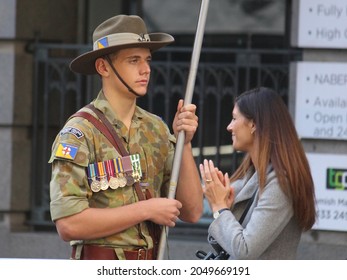 Sydney, NSW Australia - April 25 2021: People At The Anzac Day March. Young Man In An Army Camouflage Uniform And A Slouch Hat. He Is Holding A Banner As He Marches Down The Street. 