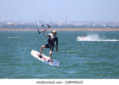 Sydney, NSW  Australia - December 23 2017: Kite Boarder Up In The Air Holding On To The Control Bar Of His Kite. He Is Wearing Strap On A Bucket Hat With Water Proof Camera An Communication Device. 
