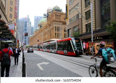 Sydney, NSW / Australia - Jan 10th 2020 - Brand New Sydney Light Rail Operating Near The Queen Victoria Building With A Delivery Cyclist Sharing The Road