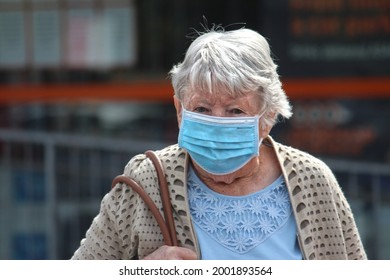 Sydney, NSW Australia - June 14, 2021: During Covid 19 Lockdown, An Elderly Woman Wearing A Surgical Face Mask Walking Across The Street With Her Handbag. 