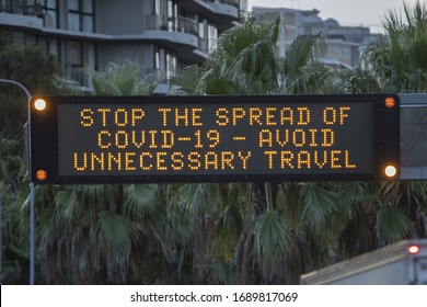 SYDNEY, NSW/AUSTRALIA - Apr 01 2020: A traffic sign reads "Stop the spread of COVID-19 – avoid unnecessary travel" amid both a coronavirus outbreak in the suburb of Bondi and new distancing measures.