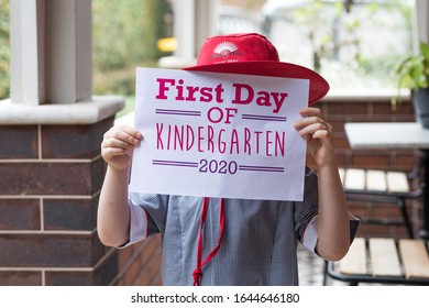 SYDNEY, NSW/AUSTRALIA – FEBRUARY 03 2020: Young Child Holding First Day Of Kindergarten Sign Dressed In Her Uniform And Hat