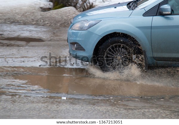 Syktyvkar,Komi /Russia,April\
10,2019/Moving car sprays puddle when heavy rain drops on\
concrete.