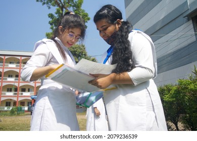 Sylhet, Bangladesh - 14 November 2021: After giving SSC (secondary school certificate) exam, two students are talking in front of the exam center with question papers in their hands.