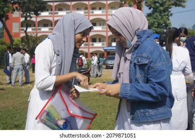 Sylhet, Bangladesh - 14 November 2021: After giving SSC (secondary school certificate) exam, two students are talking in front of the exam center with question papers in their hands.