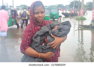 Sylhet, Bangladesh - 20 June 2022: Flood-hit Sylhet. A Woman Walks To A Safe Haven On A Flooded Road With Her Baby In Her Arms.