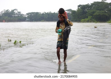 Sylhet, Bangladesh - 20 June 2022: In Flood-hit Sylhet, A Young Man Goes To A Safe Place With His Child In His Arms.