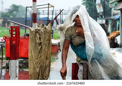 Sylhet, Bangladesh 9 Jun 2022: In The Rain, A Mentally Unbalanced Woman Is Sitting On The Street With Polythene Wrapped Around Her Head.