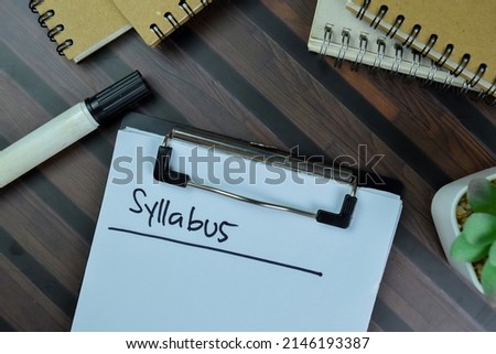 Syllabus write on a paperwork isolated on Wooden Table.