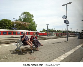 Sylt, Germany 4.6.2022 Old Couple Sitting On A Bench And Eating Ice Cream While Waiting In Railway Station For Local Train.