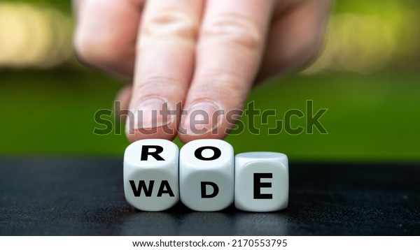 Symbol of the abortion\
process Roe versus Wade. Hand turns dice and changes the word Wade\
to Roe.