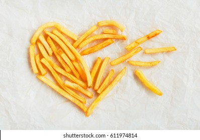 The Symbol Of Broken Heart Is Lined With French Fries On Kraft Paper. Poor Street Food, Obesity, Heart Disease. French Fries