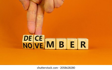 Symbol for the change from November to December, winter. Businessman turns wooden cubes and changes the word 'November' to 'December'. Beautiful orange background, copy space. Happy December concept.