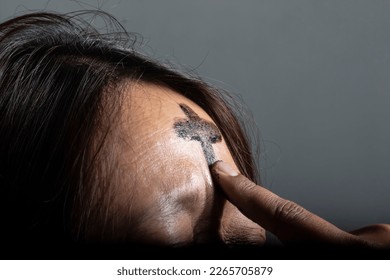 the symbol of a cross made of ashes placed on a woman's forehead during Ash Wednesday celebrations, Medan, February 23, 2023
