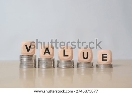 Symbol for decreasing value. Dice placed on stacks of coins form the word "value"