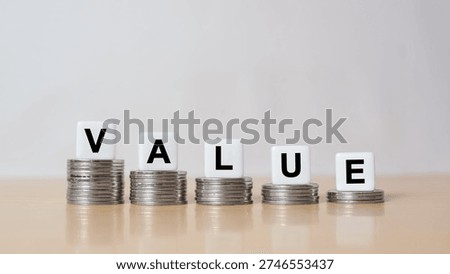 Symbol for decreasing value. Dice placed on stacks of coins form the word "value"