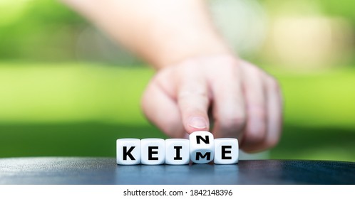 Symbol for fighting germs. Hand turns dice and changes the German word "Keime" (germs) to "keine" (no). - Shutterstock ID 1842148396