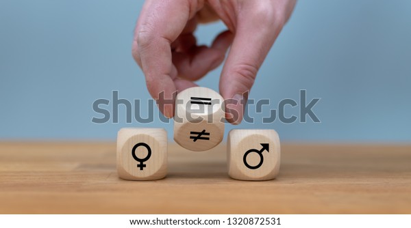 Symbol\
for gender equality. Hand turns a dice and changes a unequal sign\
to a equal sign between symbols of men and\
women.