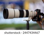 Symbol image sports photographer, sports photography: Close-up of a large telephoto lens in a football stadium