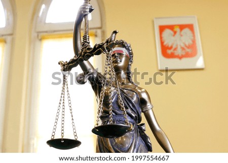 Symbol of justice - statue of themis with white-and-red colored sash on eyes, and Polish national emblem, closeup, shallow depth of field