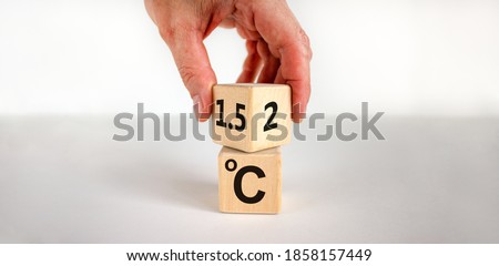 Symbol for limiting global warming. Male hand turns a cube and changes the expression '2 C' to '1.5 C', or vice versa. Concept. Beautiful white background, copy space.