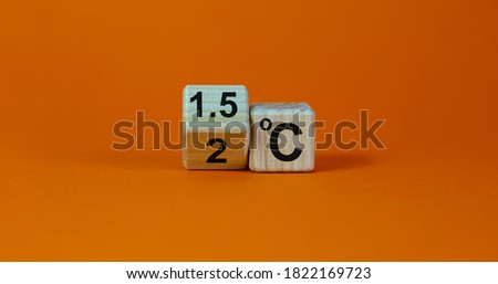 Symbol for limiting global warming. Turned a cube and changed the expression '2 C' to '1.5 C', or vice versa. Concept. Beautiful orange background, copy space.
