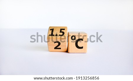 Symbol for limiting global warming. Turned a cube and changed the expression '2 C' to '1.5 C', or vice versa. Concept. Beautiful white table, white background, copy space.