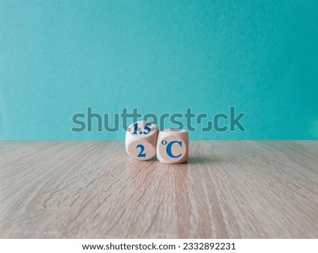 Symbol for limiting global warming. Turned a cube and changed the expression 2 C to 1.5 C, or vice versa. Concept. Beautiful wooden table, blue background, copy space.