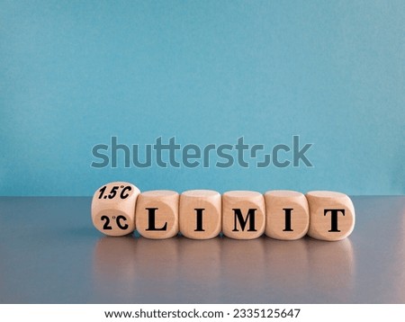 Symbol for limiting global warming. Turned the cube and changes the expression 2 C limit to 1.5 C limit or vice versa. Beautiful grey table, blue background. Ecological concept.