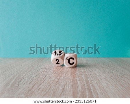 Symbol for limiting global warming. Turned a cube and changed the expression 2 C to 1.5 C, or vice versa. Concept. Beautiful wooden table, blue background, copy space.