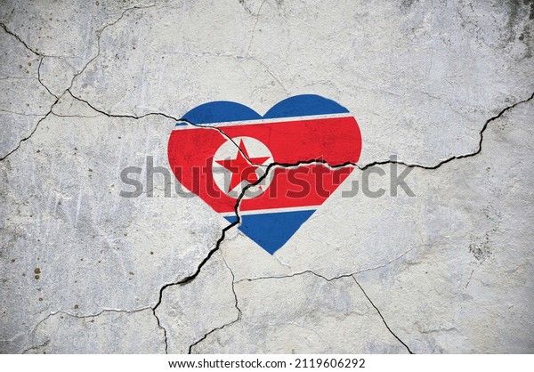 The symbol of the\
national flag of North Korea in the form of a heart on a cracked\
concrete wall. Concept.